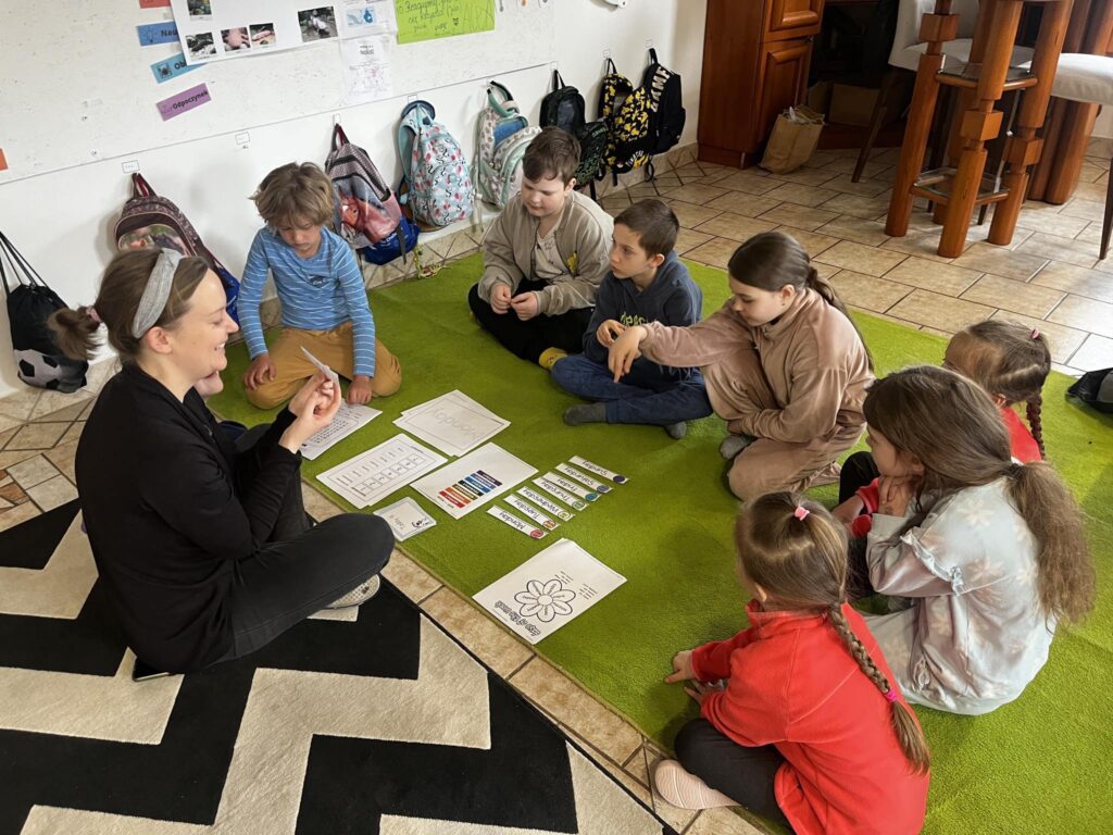Swobodna edukacja w Domu Rozwoju Dzieci razem z nuczycielem pracujace nad zadaniem na podłodze